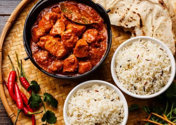 Chicken tikka masala spicy curry meat food in cast iron pot with rice and naan bread close up